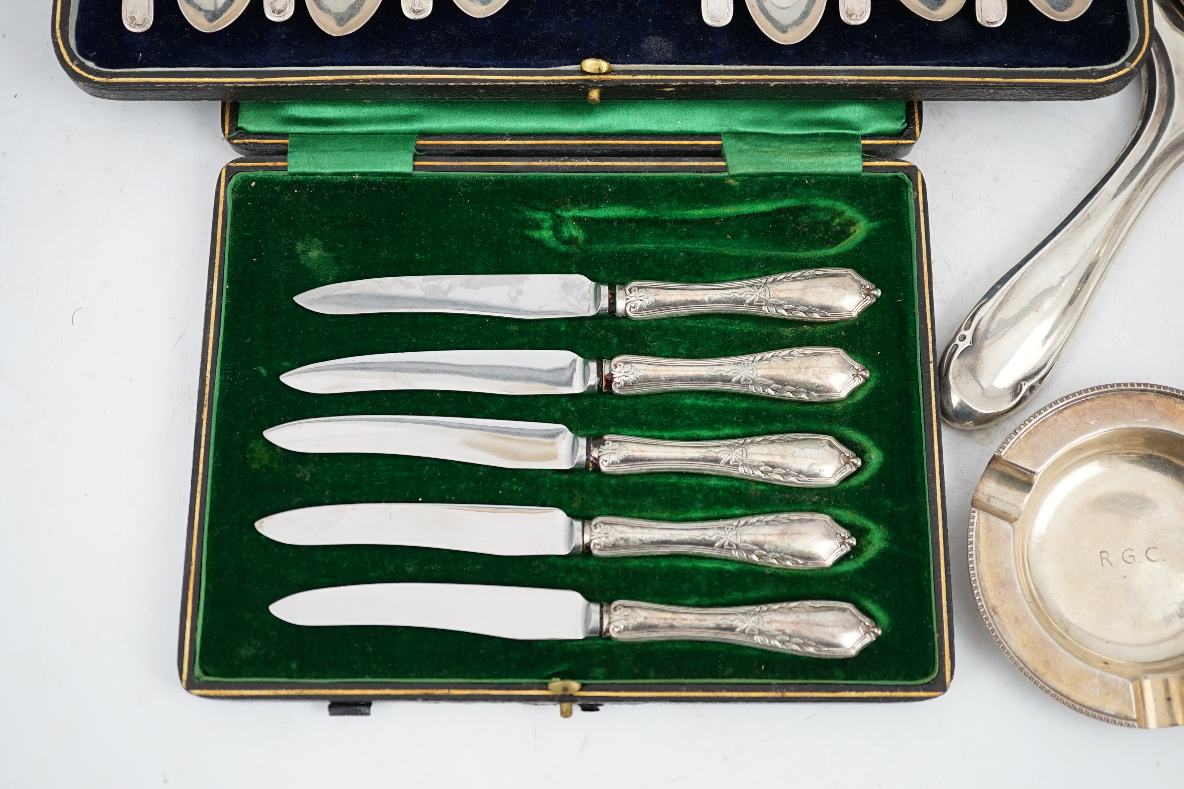 A cased set of twelve George V silver teaspoons with sugar tongs, Sheffield, 1912, two silver hand mirrors, a silver sugar bowl and cream jug, a silver ashtray, a George III silver caddy spoon and cased plated tea knives